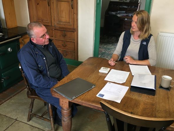 Farmer and consultant sat at kitchen table reviewing paper work